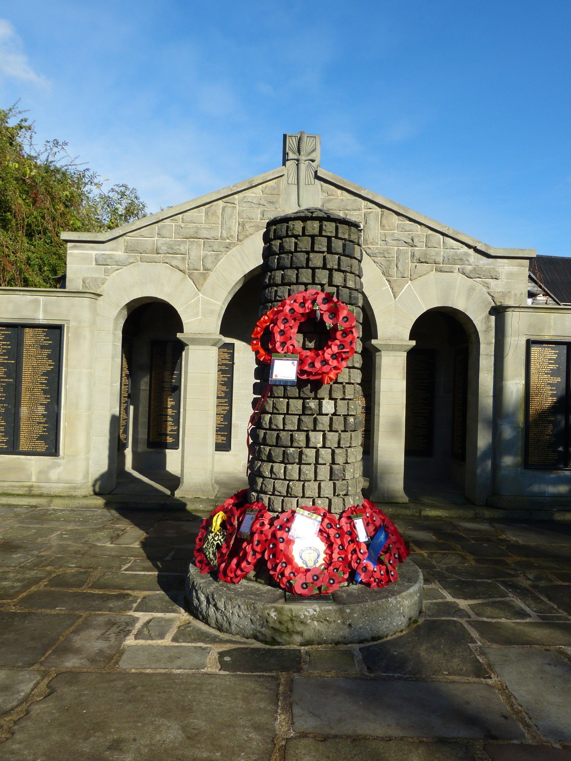A stone pillar with red wreaths on it in front of a building