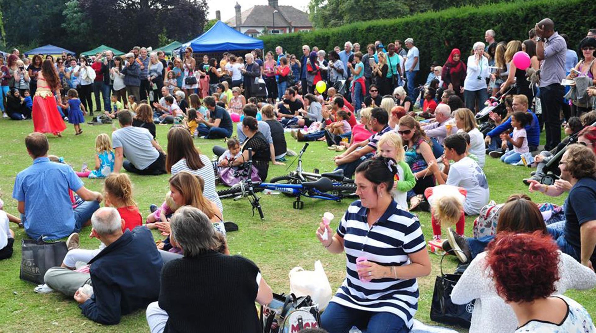 A large group of people are sitting on the grass in a park.