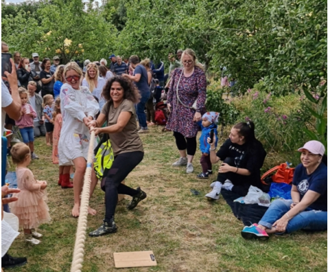People dancing and watching at an outdoor garden gathering on a grassy path.