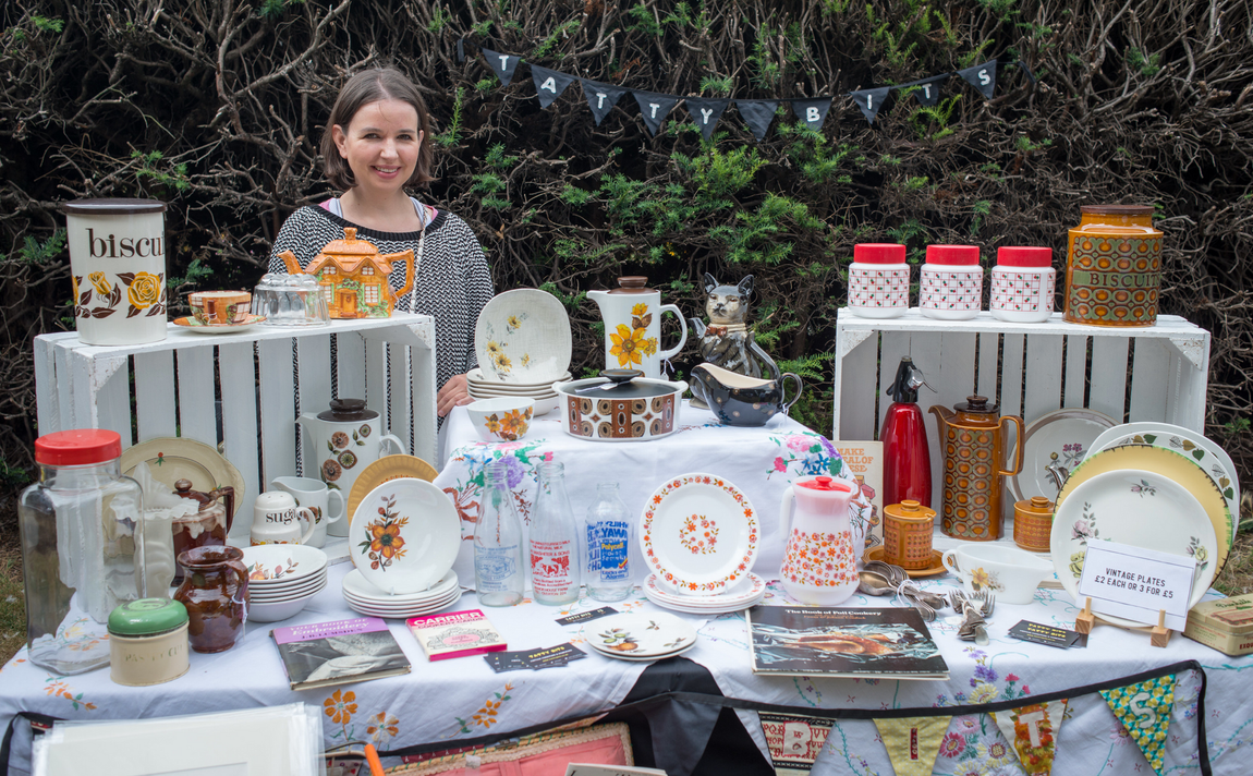 Vendor displaying decorative dishes and jars at an outdoor market stall