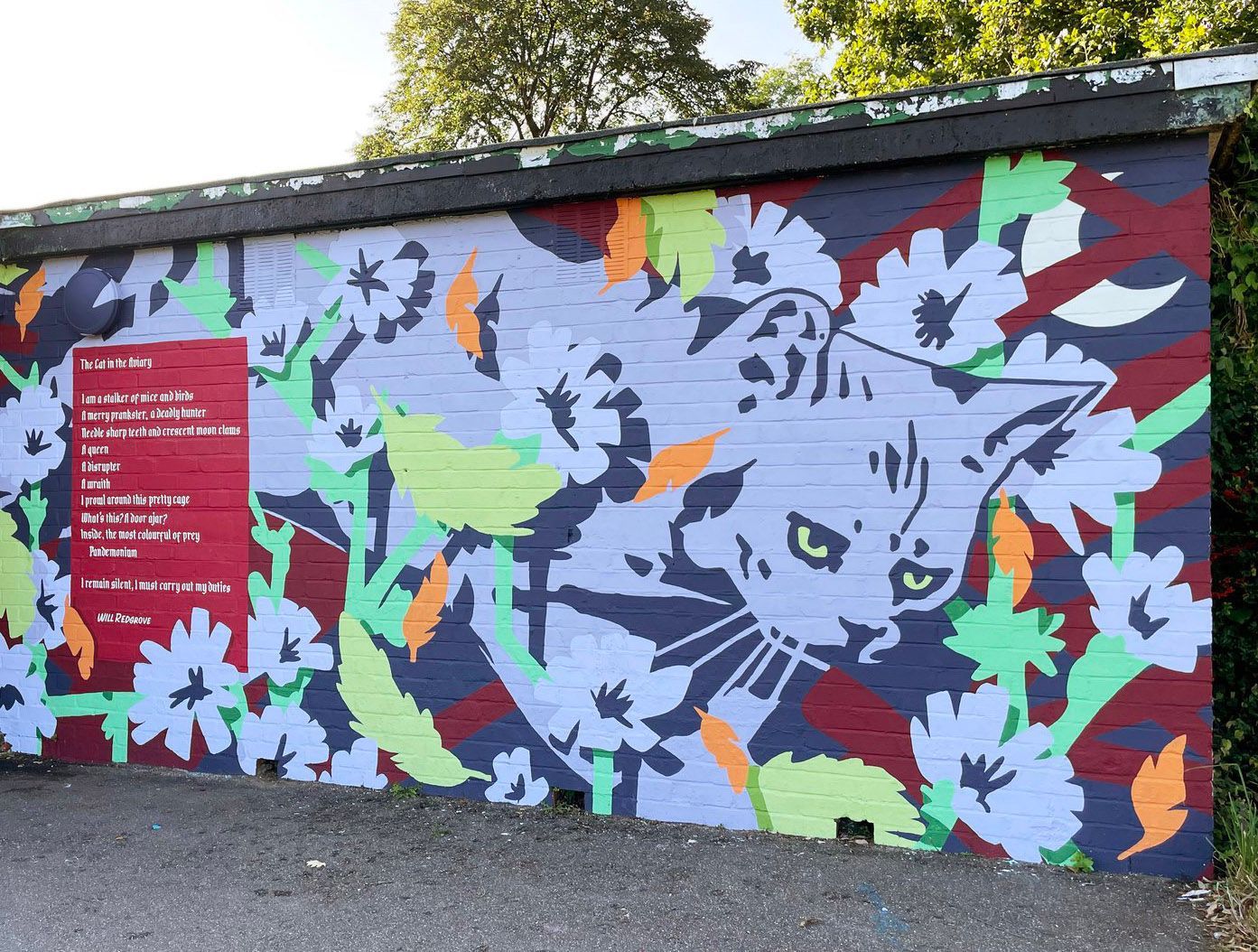 A wall with a painting of a cat and flowers on it