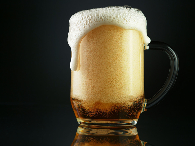 A glass of beer with foam coming out of it