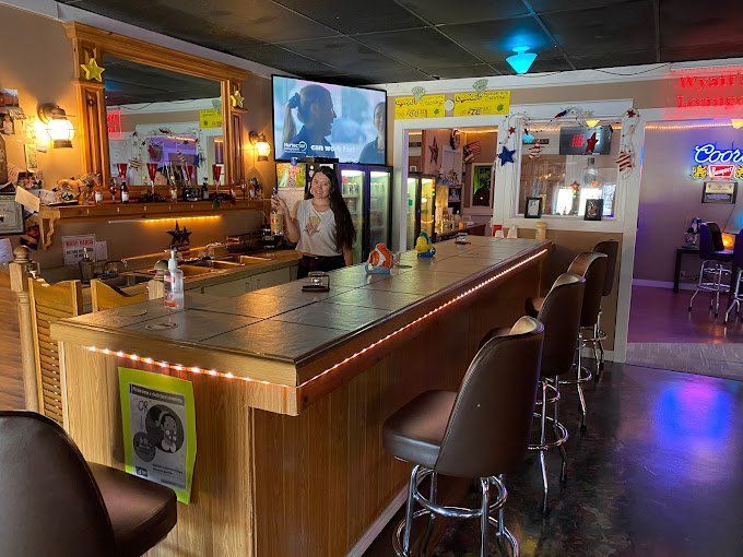 A woman is standing behind a bar in a restaurant.