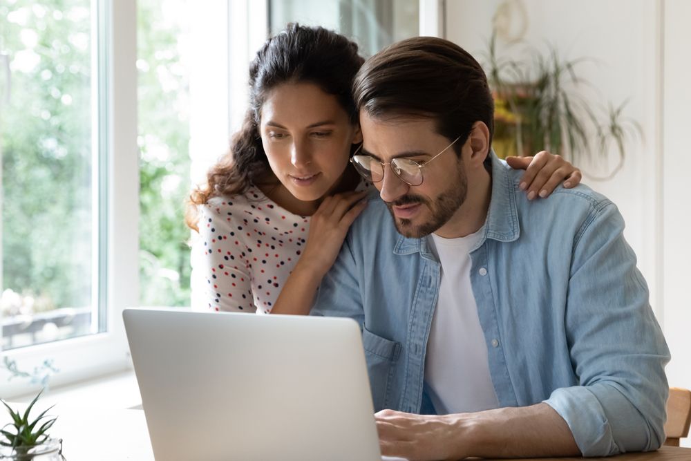 A man and a woman are looking at a laptop computer.