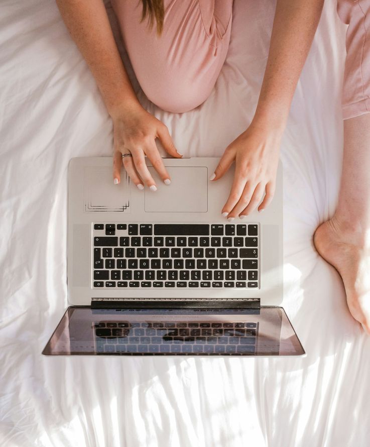 A woman is sitting on a bed using a laptop computer