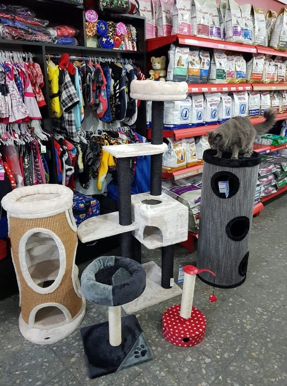 Árboles rascadores y postes para gatos expuestos en un pasillo de una tienda de mascotas, en color blanco, negro y rojo.