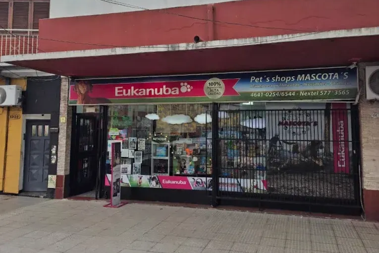 Fachada de una tienda de mascotas con toldo rojo, ventanas enrejadas y letrero de Eukanuba en una calle.