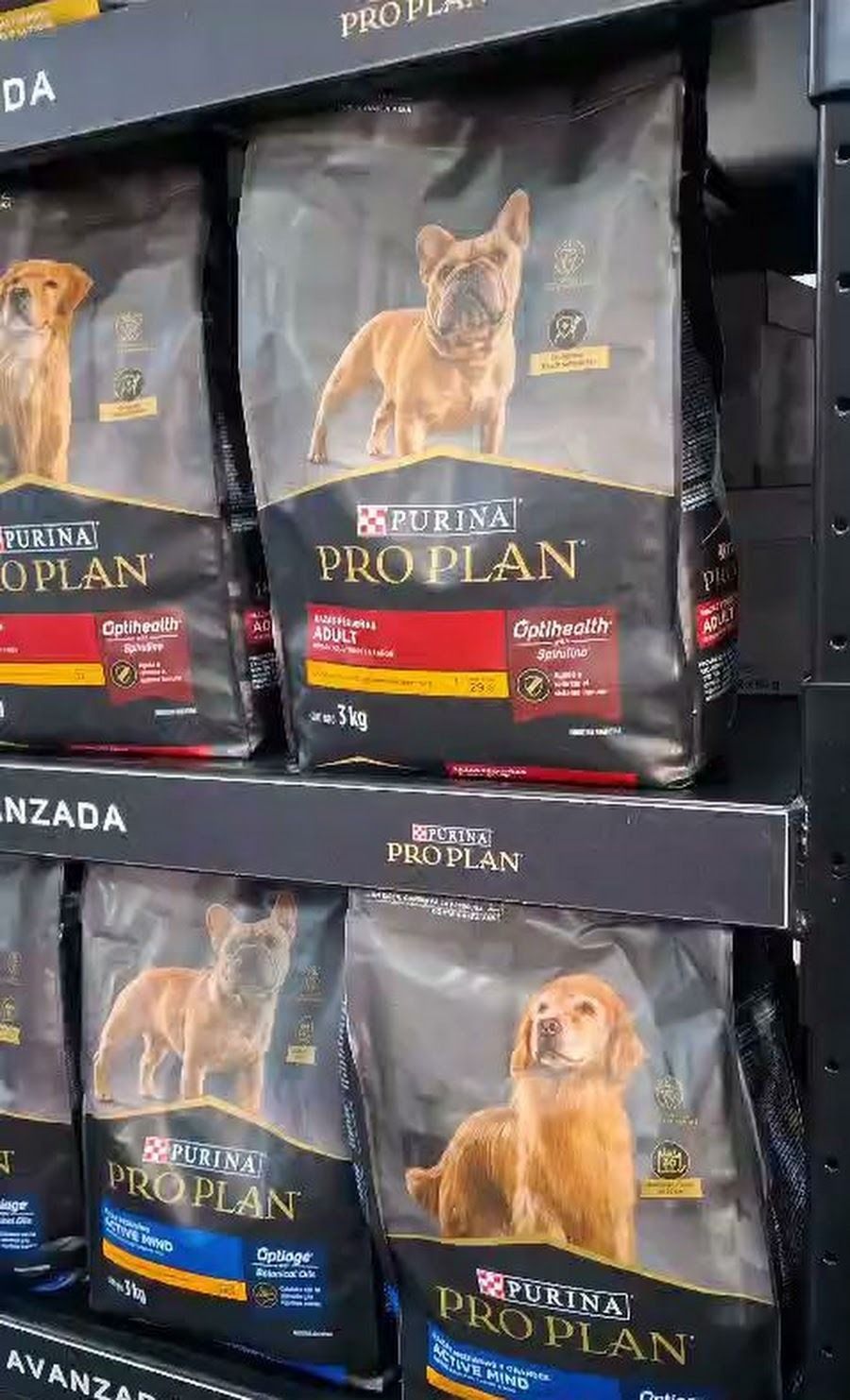 Estantes llenos de bolsas de comida para perros Pro Plan en un pasillo de una tienda de mascotas.
