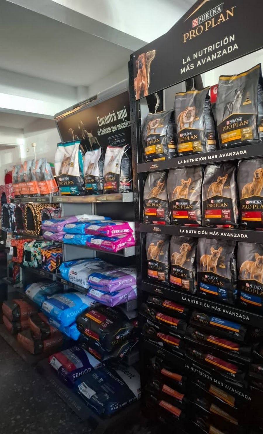 Estantes repletos de bolsas y cajas de comida para mascotas de diferentes tamaños en un pasillo de la tienda.