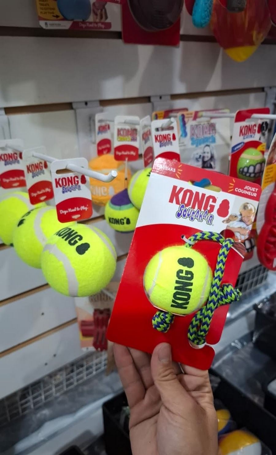 Una mano sostiene un paquete rojo de un juguete para perros KONG 