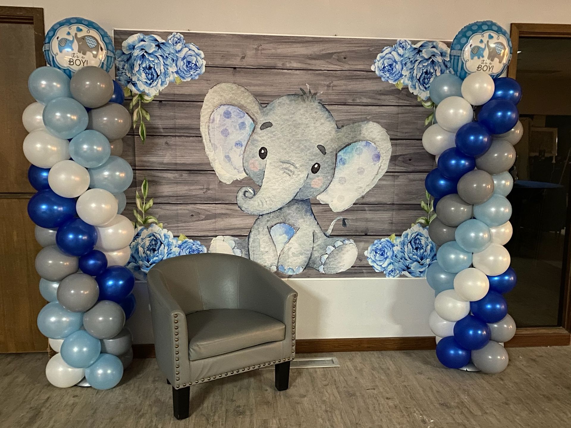 A chair is sitting in front of a wall decorated with balloons and a picture of an elephant.