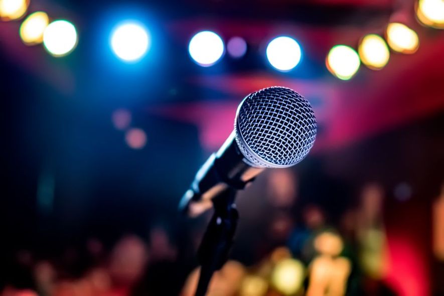 A microphone is sitting on a stage in front of a crowd.