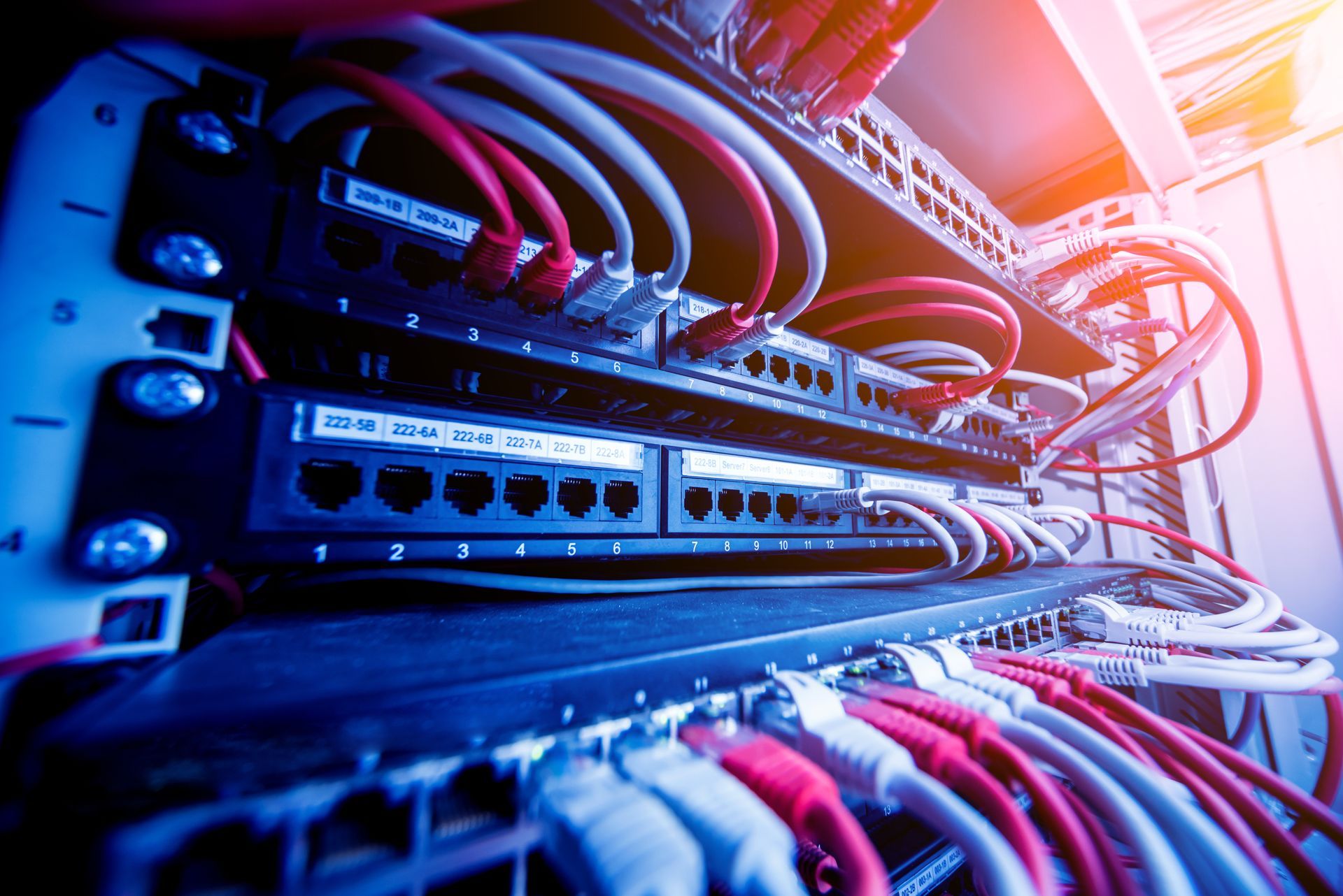 A server rack showing multiple ports and connected red and white Ethernet cables in a data center.