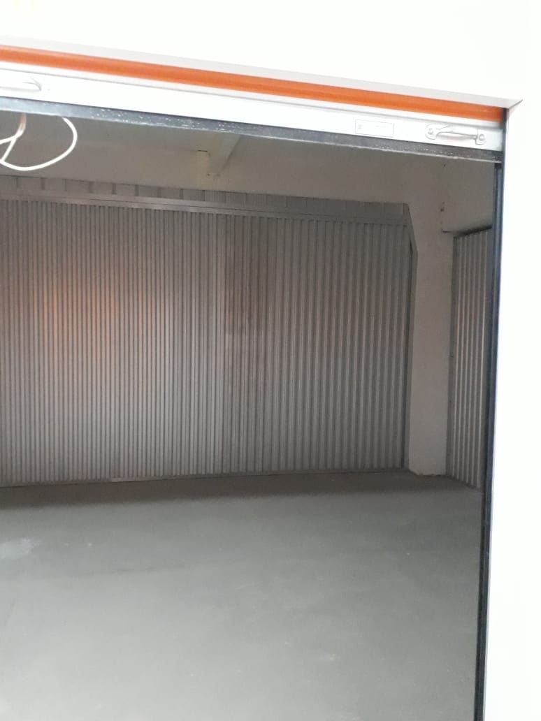 Pasillo de trastero con puertas enrollables grises y suelo de hormigón pulido.