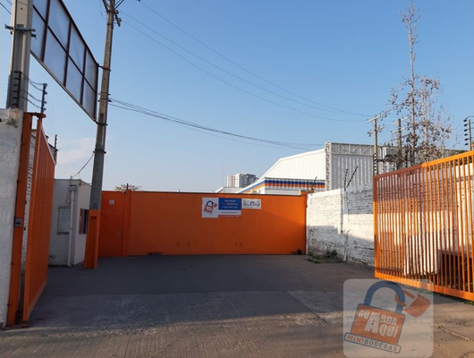 Pasillo de almacén con cajas de cartón apiladas en estanterías metálicas y palés.
