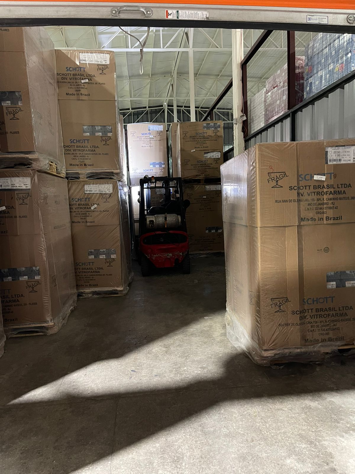 Una carretilla elevadora mueve cajas paletizadas en un pasillo de un almacén entre palés de envío apilados.