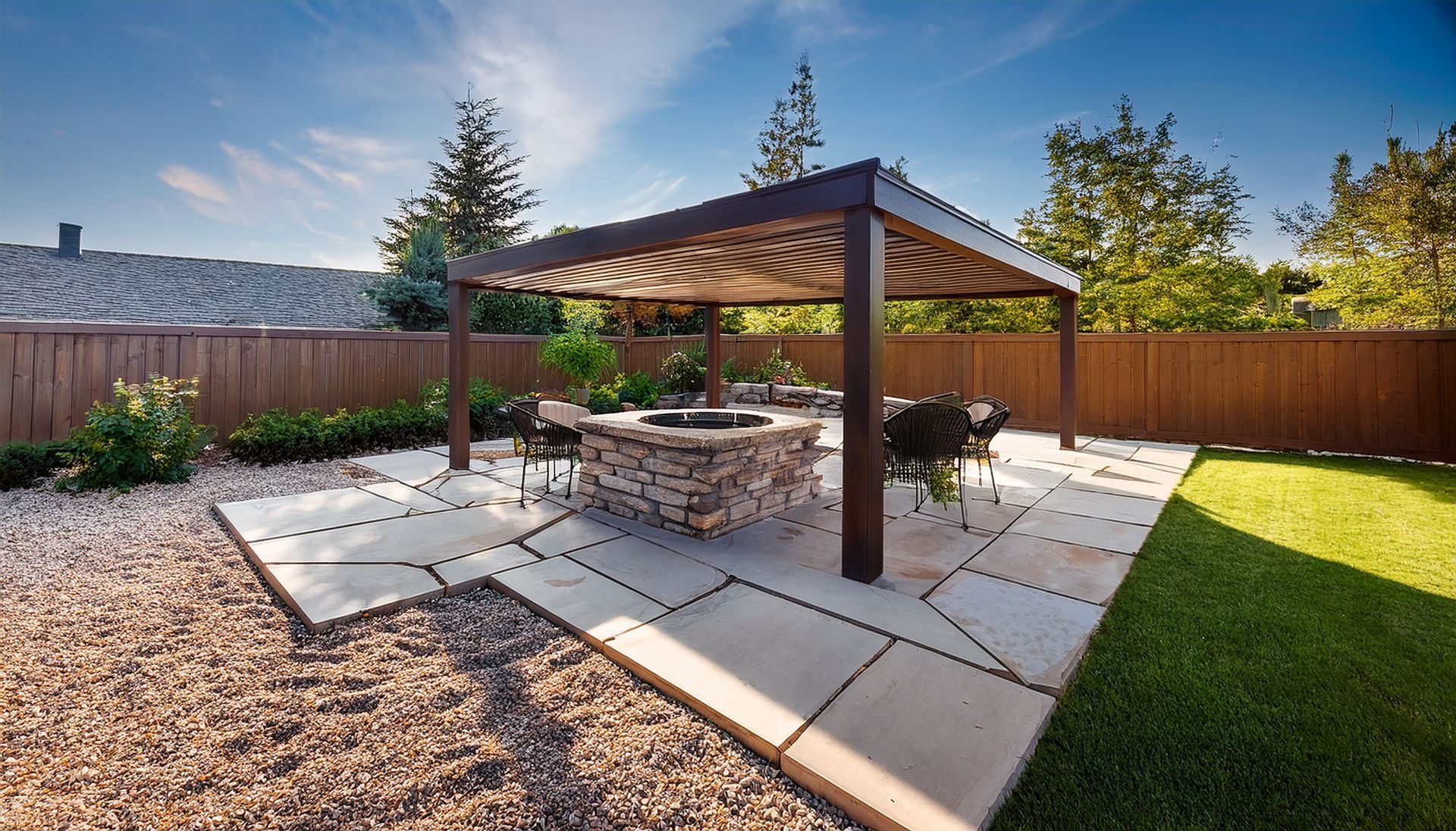 Modern patio with stone fire pit and pergola by landscaping design services.