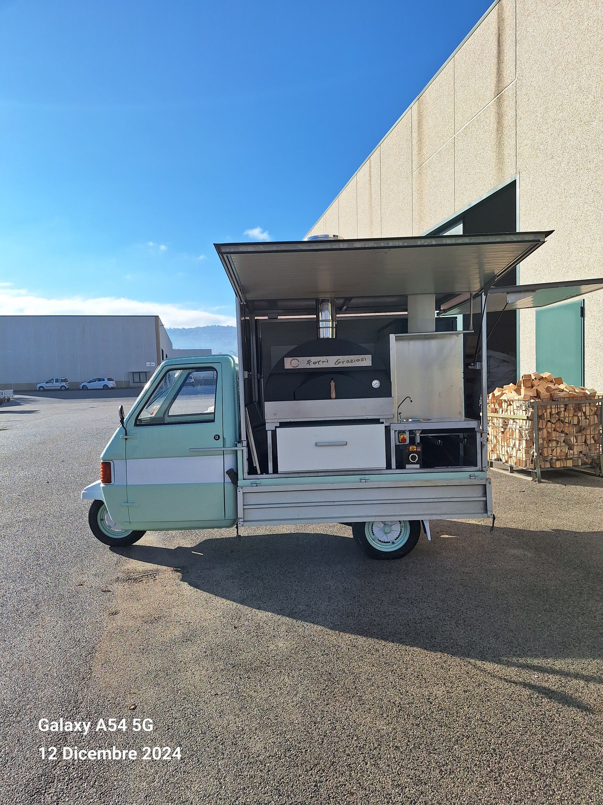 Un camioncino che vende cibo verde è parcheggiato davanti a un edificio.