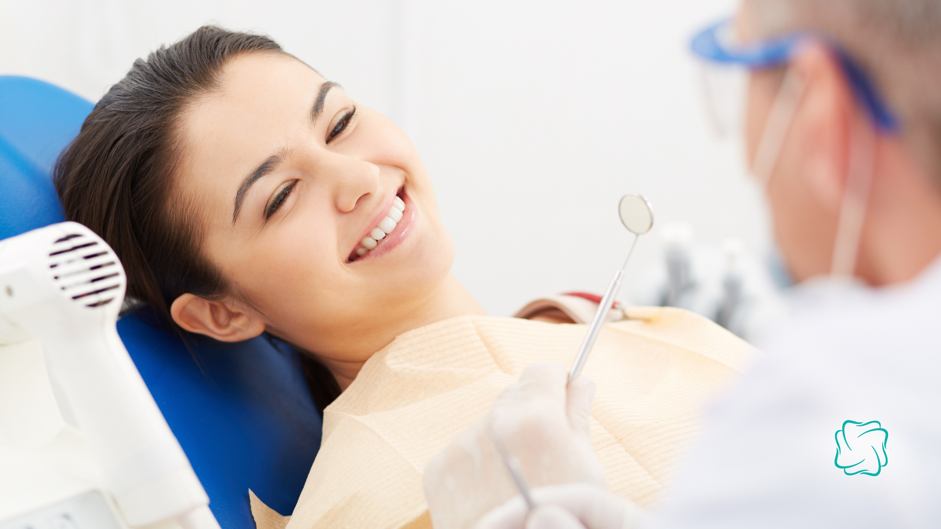 Woman smiling at dentist during an exam, in a dental chair.
