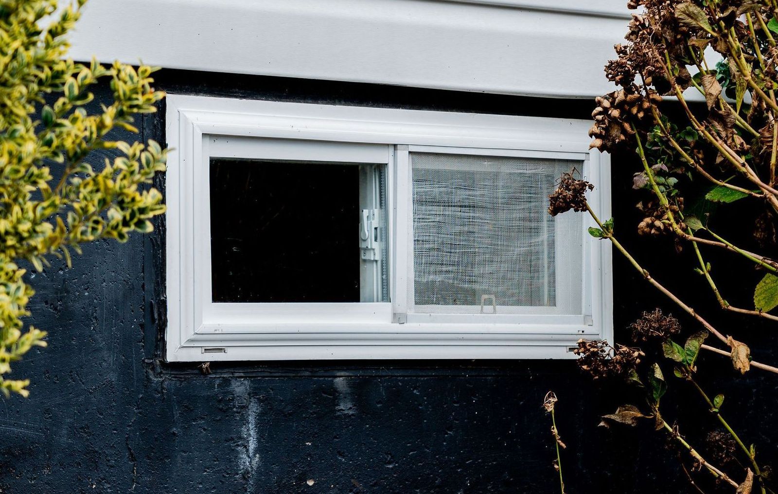 A black wall with a white rolling window on it