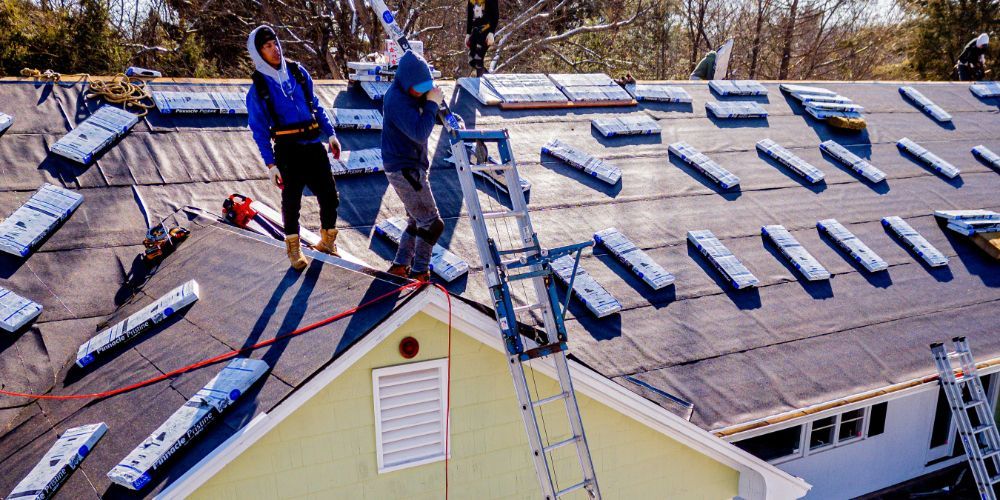 Two men are working on the roof of a house.