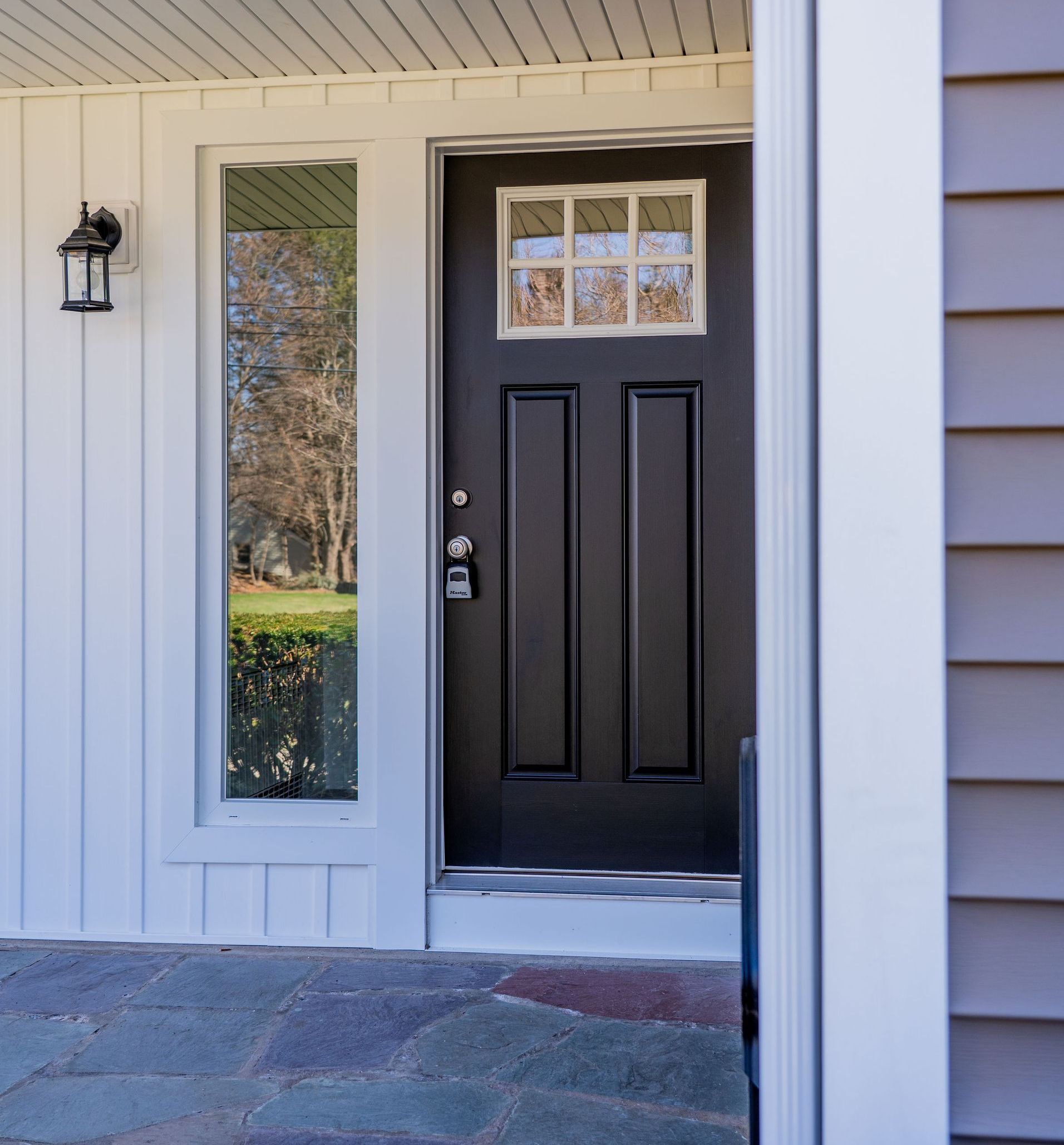 A black front door with a lantern on the side of it