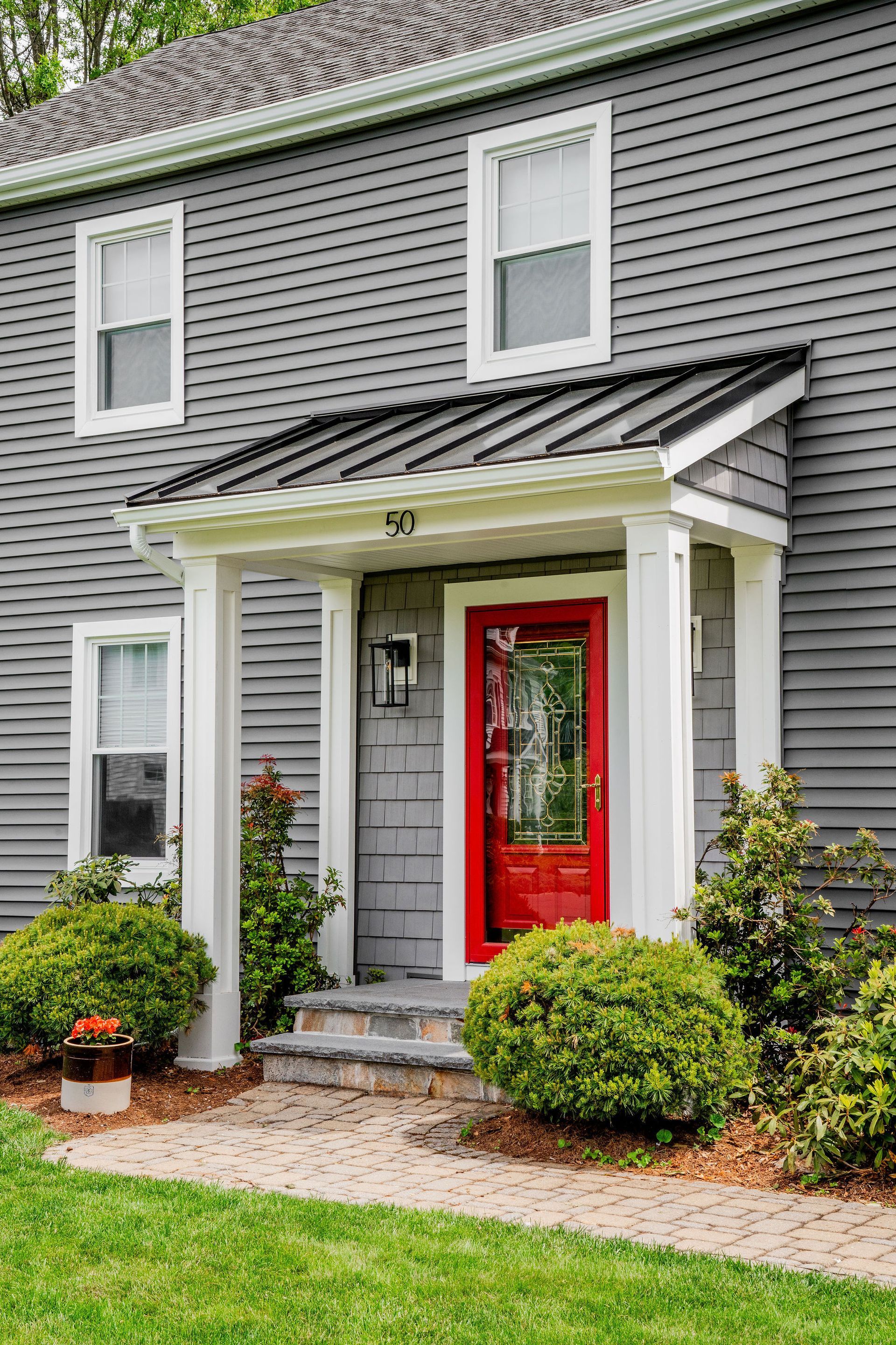 Gray house with a bright red front door, white trim, and landscaped entryway