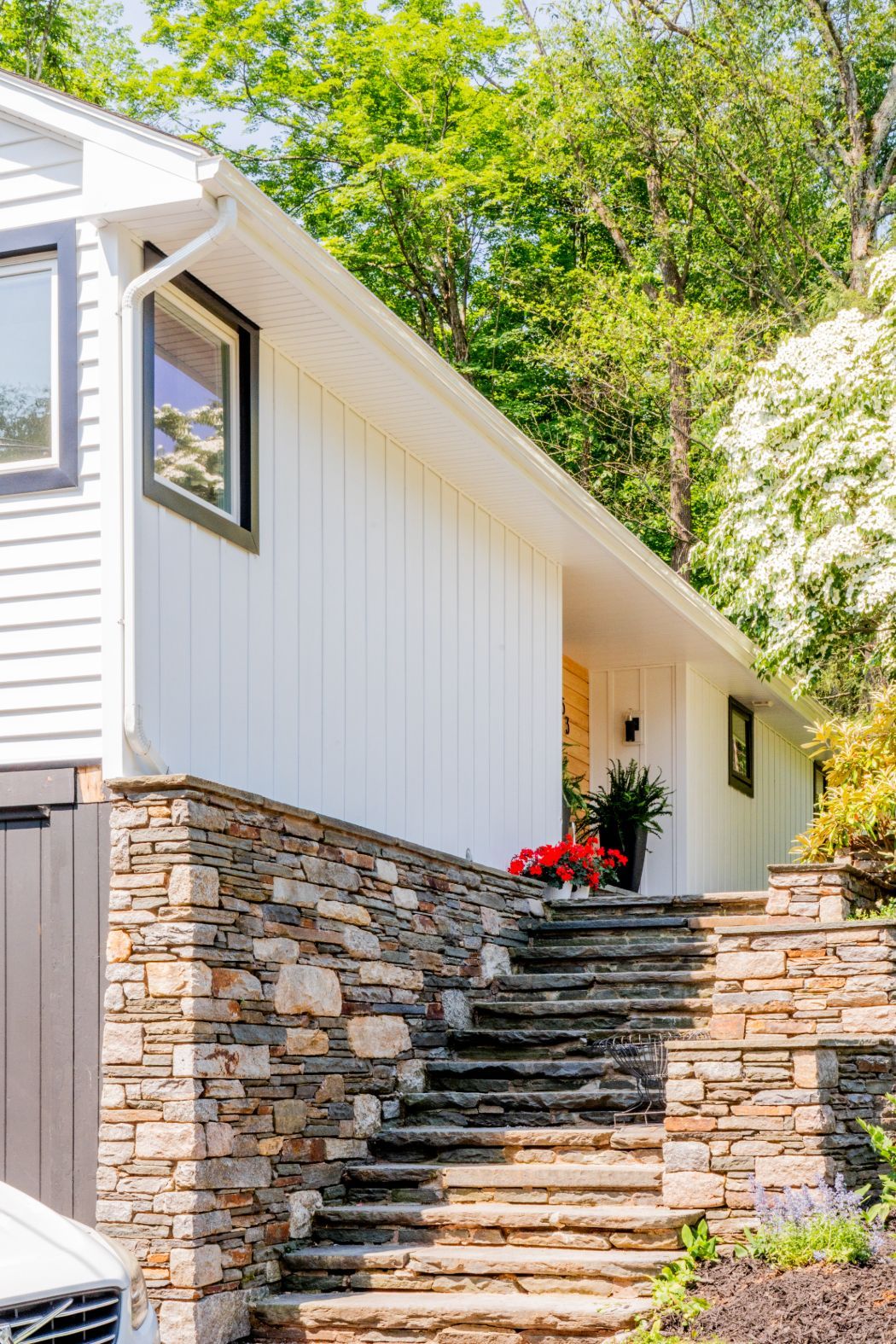 Single-story house with white siding, yellow door, and a blooming white tree in the front yard.