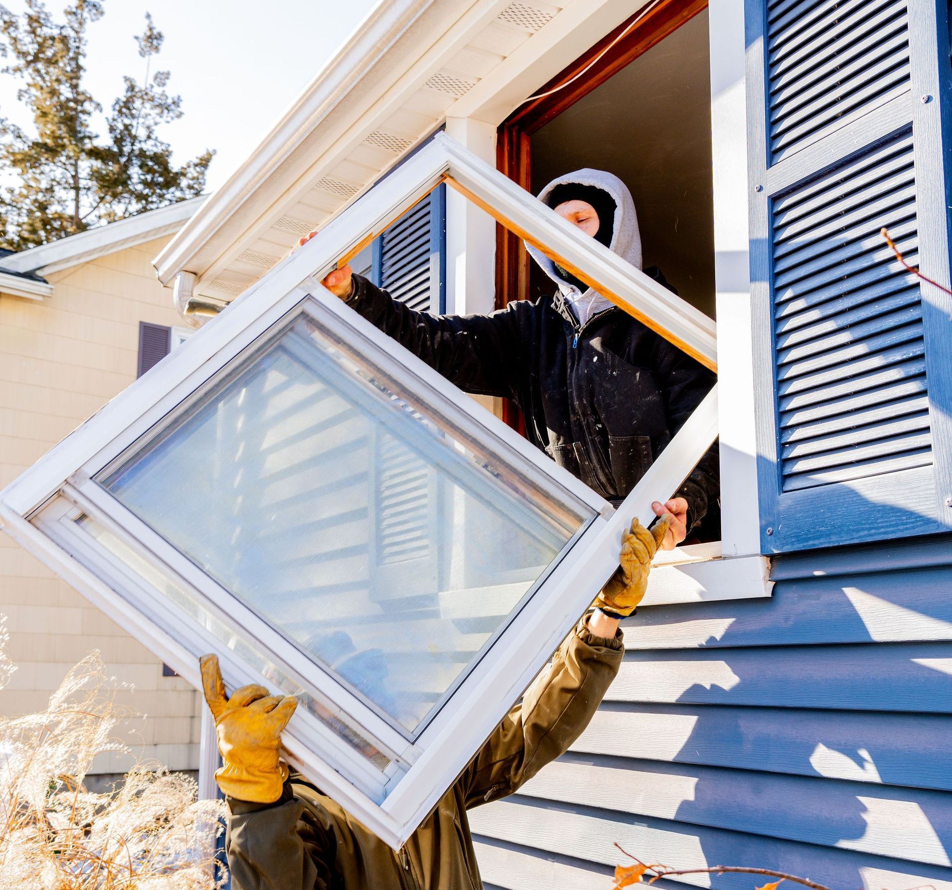 A man is holding a window in front of a house.