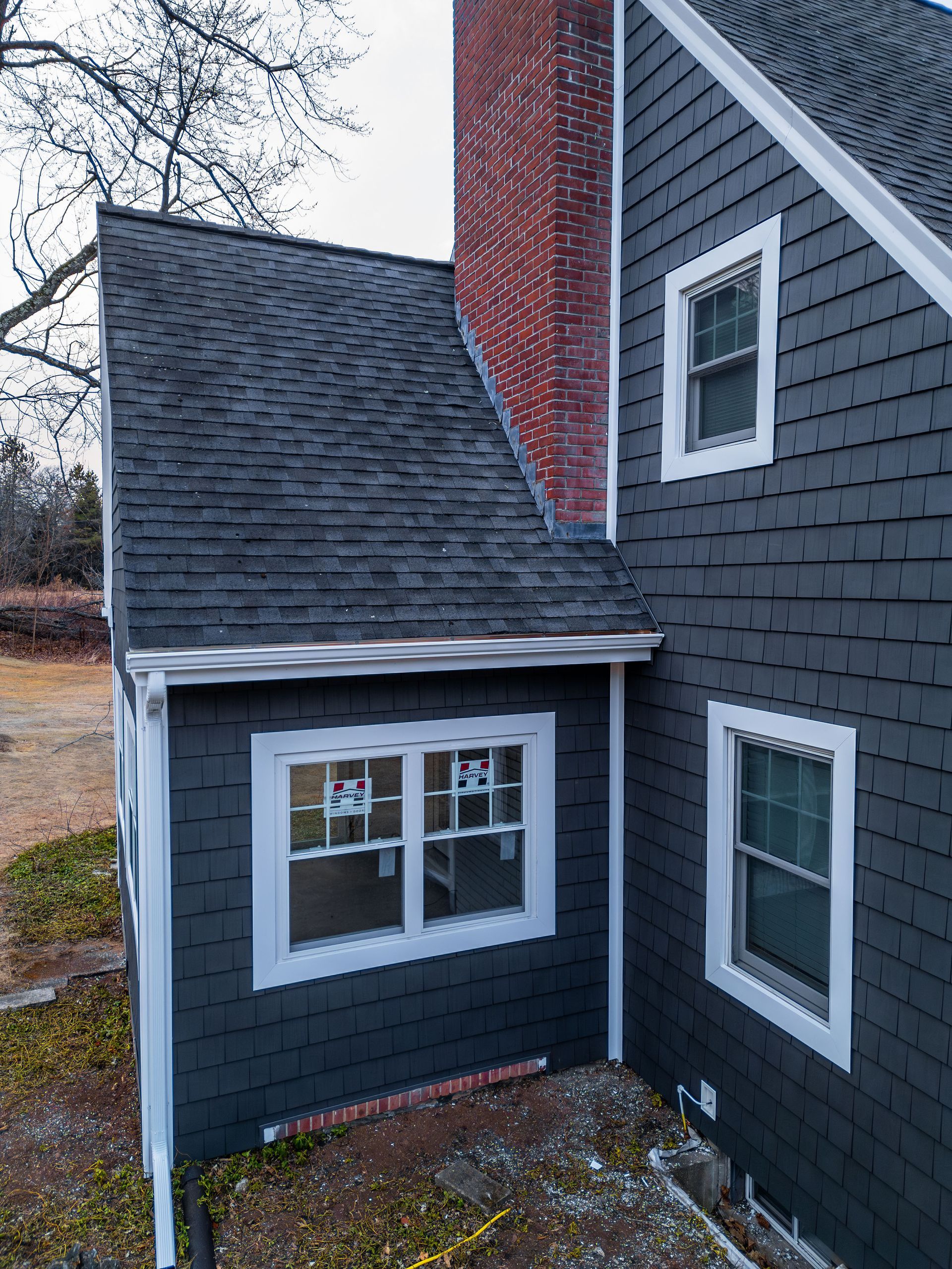 Dark gray house with white trim and red brick chimney.