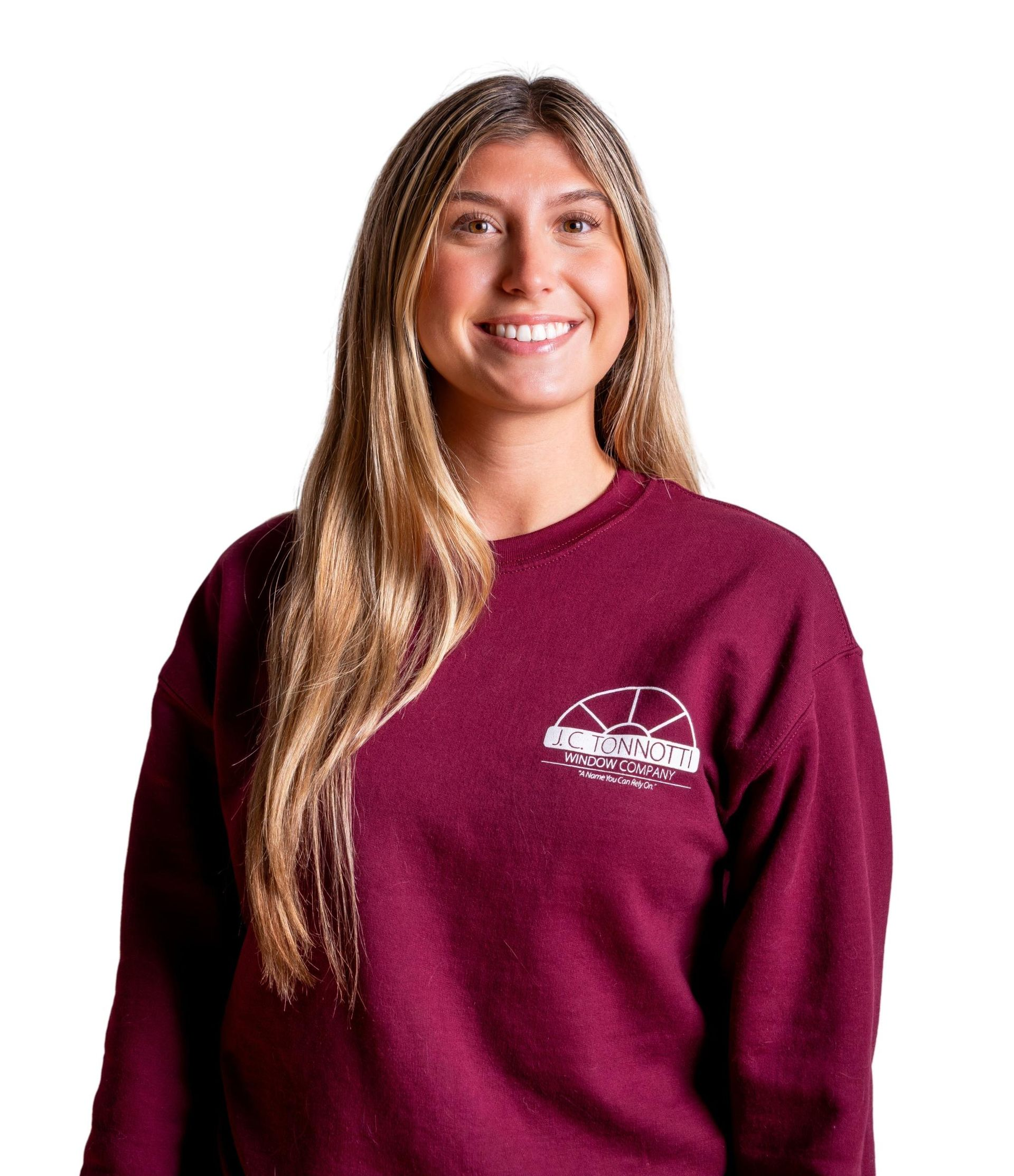 Woman with long blonde hair, smiling, wearing a maroon sweatshirt with a white logo.