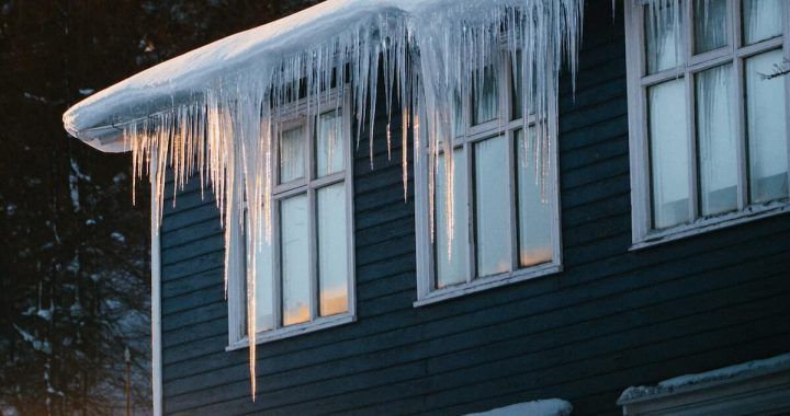 Icicles are hanging from the roof of a house.