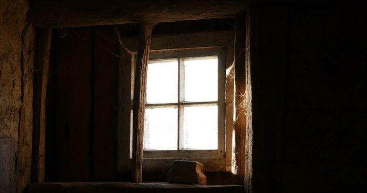 A window in a dark room with a light coming through it.