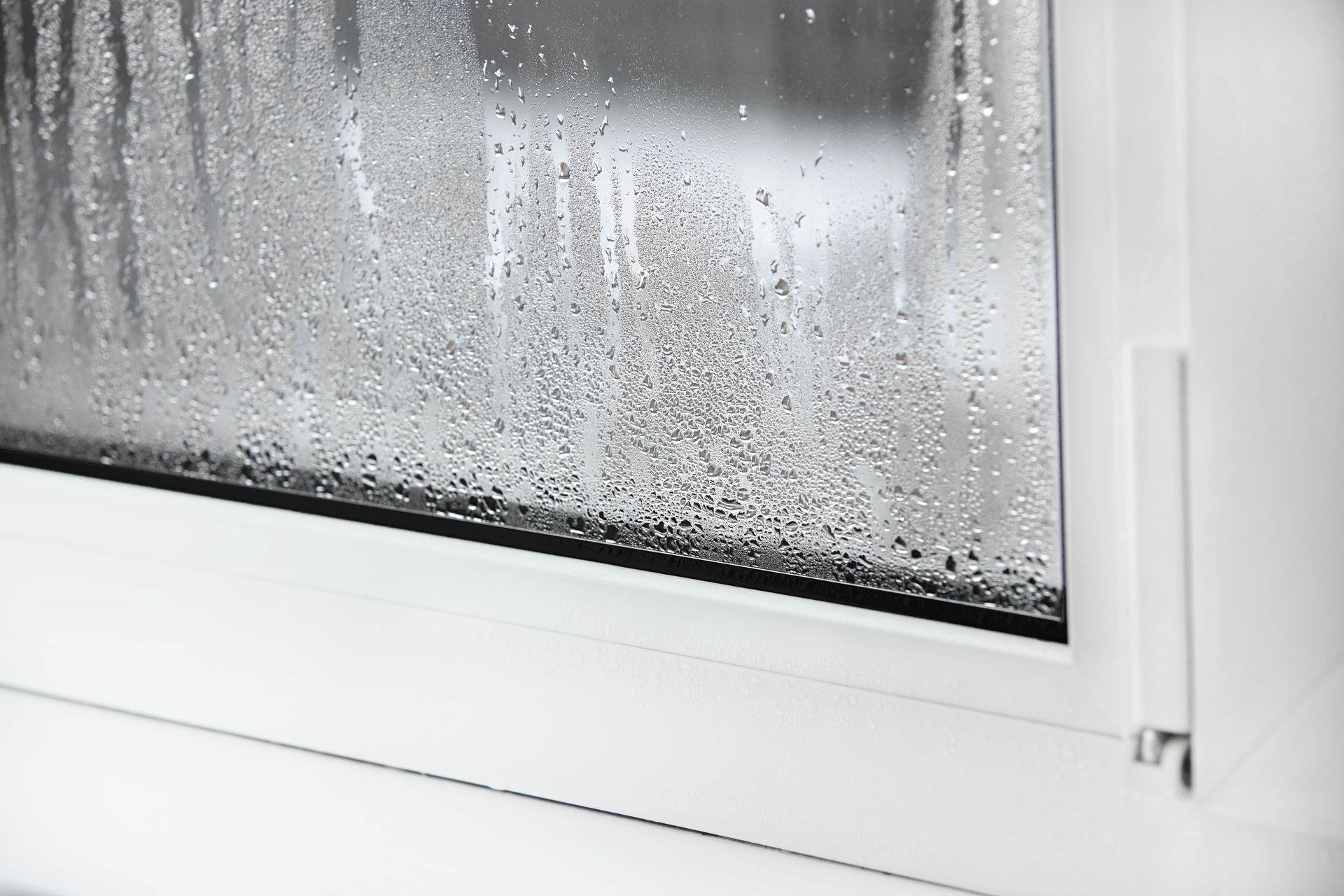 Rain droplets on a frosted window with a white frame