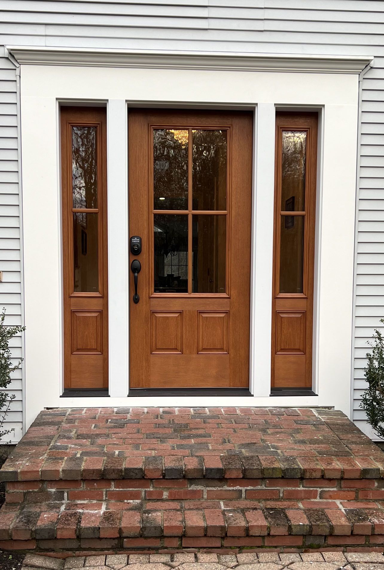 The front door of a house with a wooden door and brick steps.