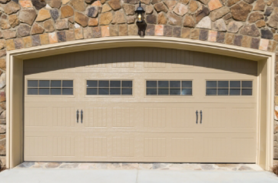 A tan garage door with a stone wall behind it