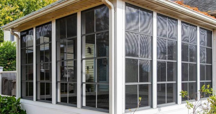 A screened in porch with lots of windows on a house.