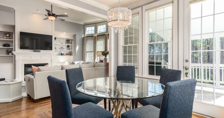 A dining room with a glass table and chairs and a ceiling fan.