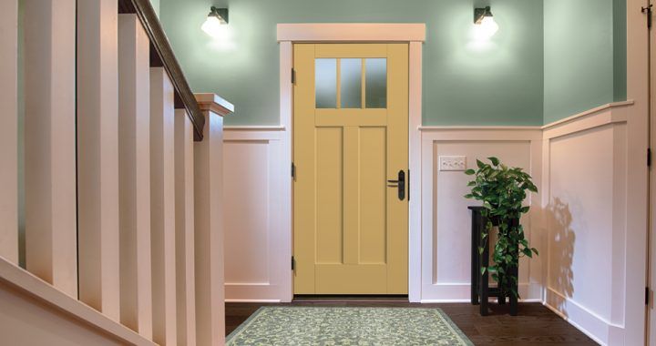 A hallway with a yellow door and stairs leading up to it.