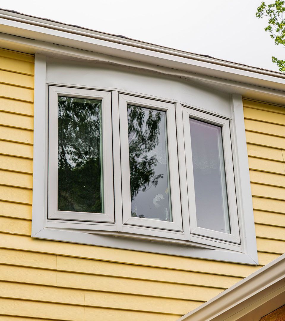 A yellow house with a white window on the side