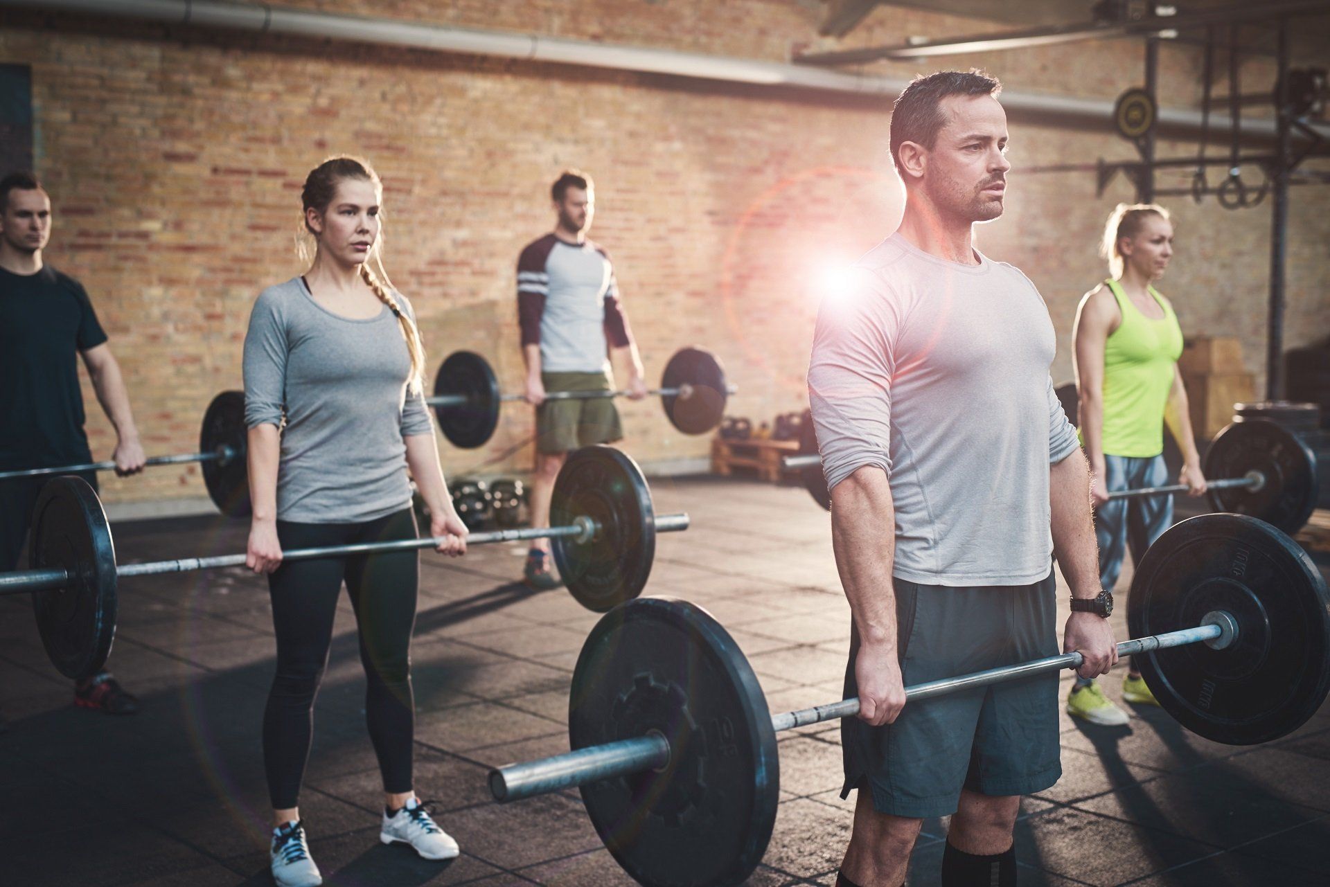 A group of people are lifting barbells in a gym.
