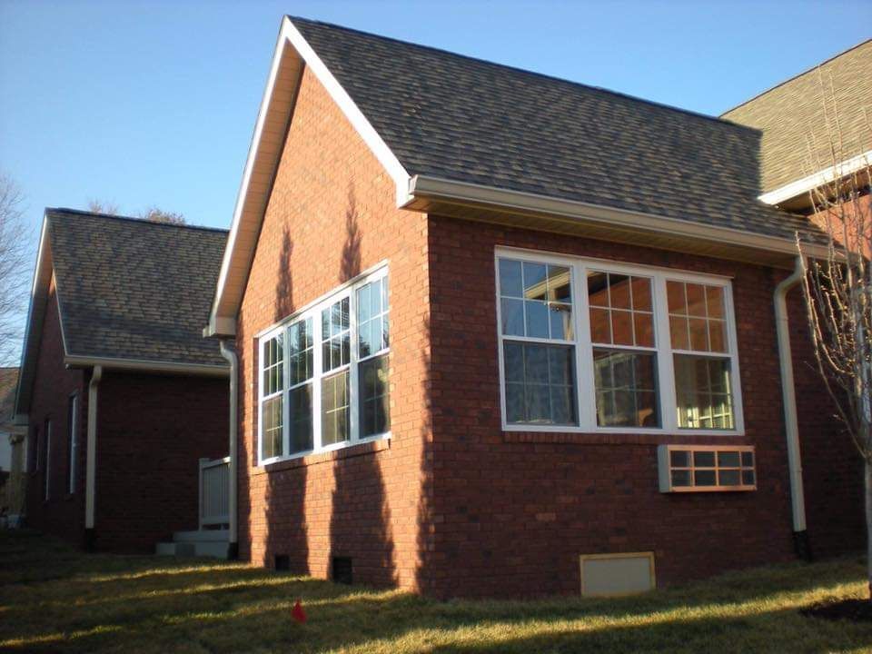 Brick building with multiple windows and a dark roof.