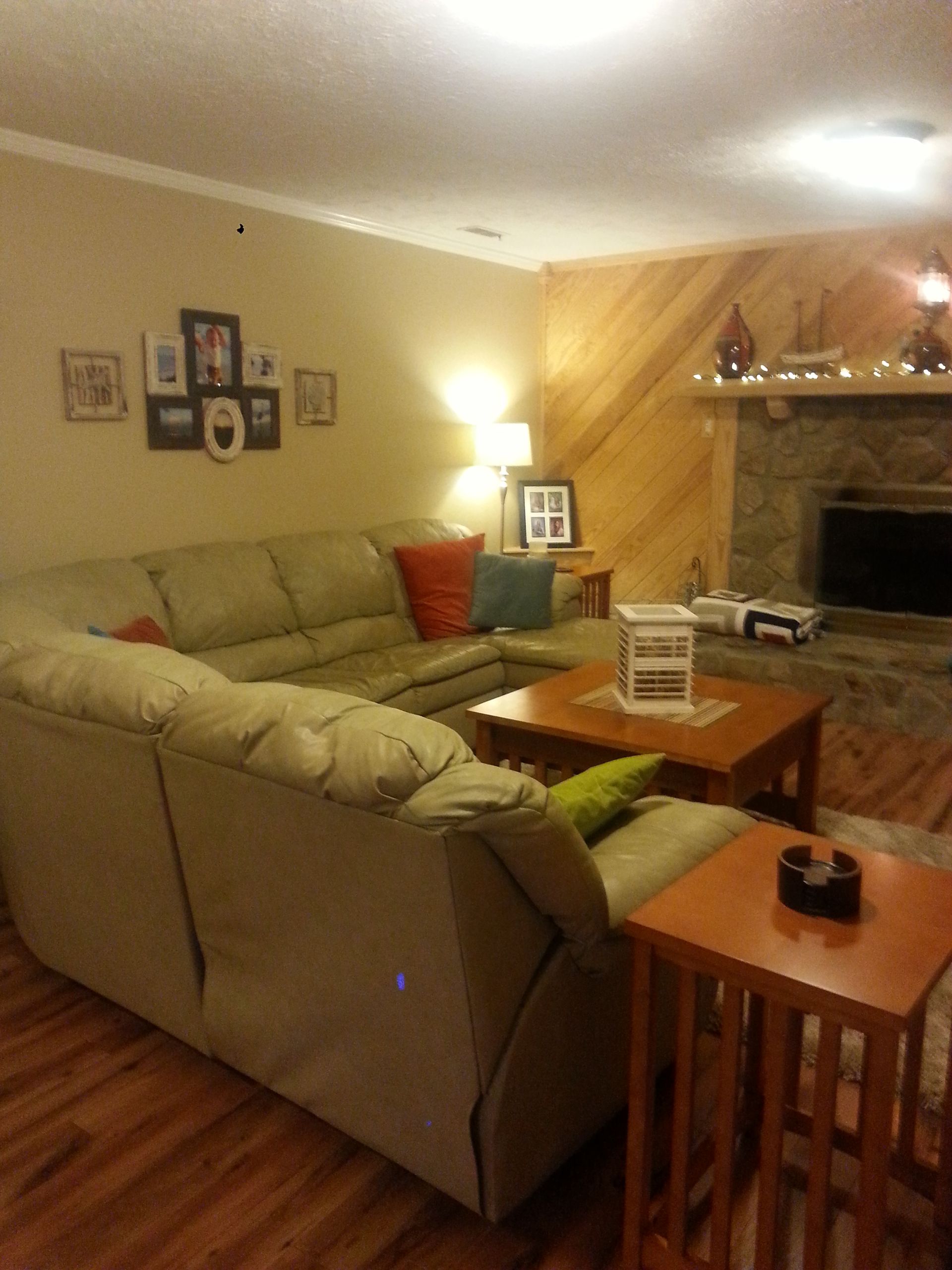Cozy living room with a sectional sofa, wooden coffee tables, and a stone fireplace. Earth-toned decor.