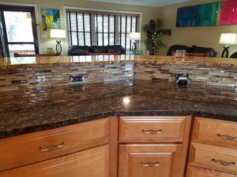 Kitchen countertop with brown granite, light brown cabinets, and a tile backsplash.