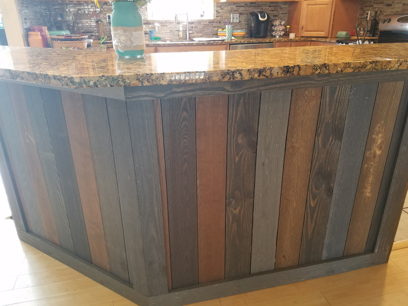 Wooden kitchen island with multi-colored planks and granite countertop.