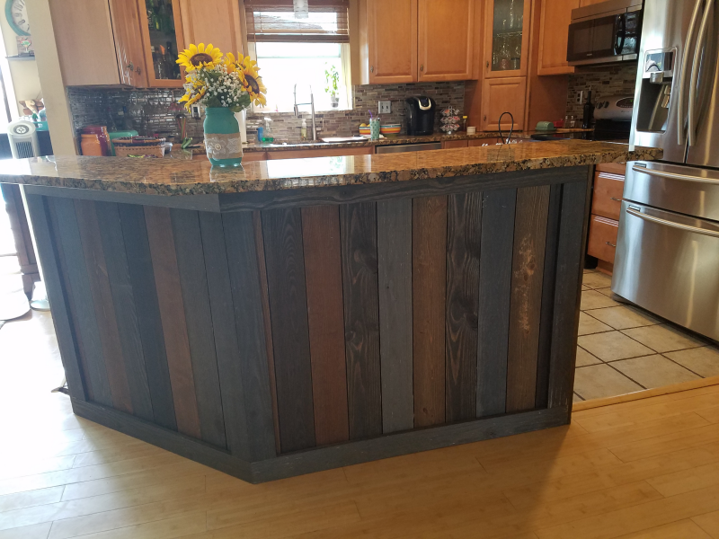Kitchen island with granite countertop and multi-tone wood paneling.