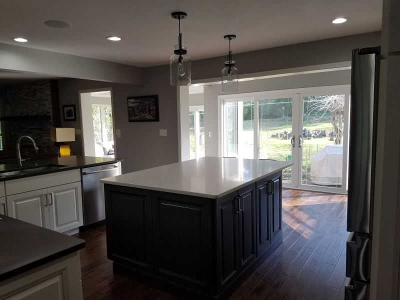 Kitchen with dark island, white countertop, and sliding glass doors to a yard.