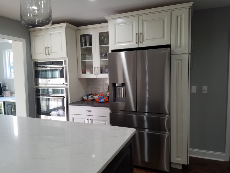 Kitchen with white cabinets, stainless steel refrigerator, and built-in ovens.