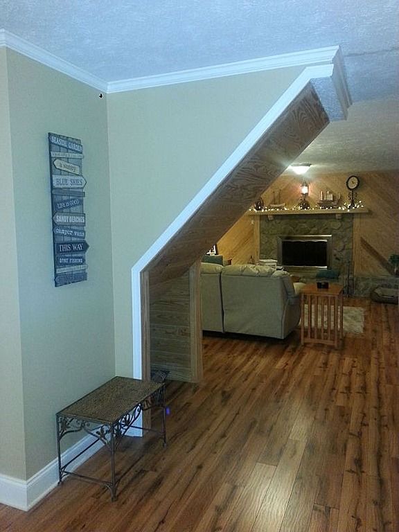 Entryway with wooden floor, beige walls, and a view into a living room with a fireplace and couch.