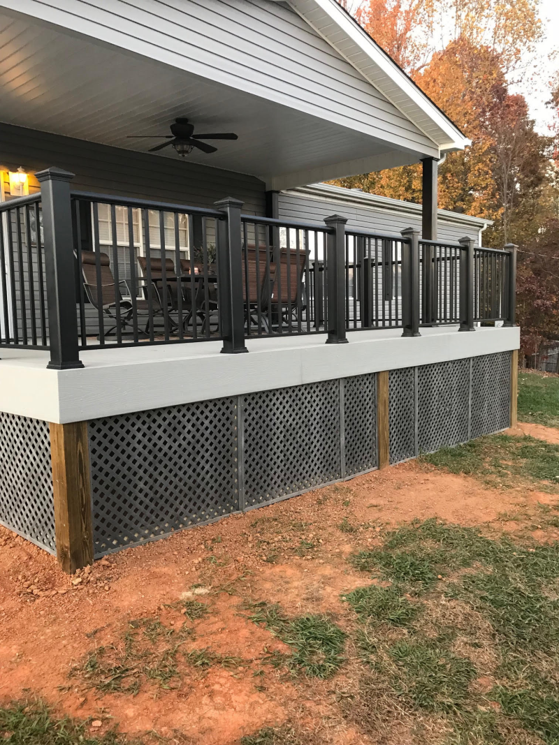 Gray deck with black railing and lattice skirting, overlooking a yard.